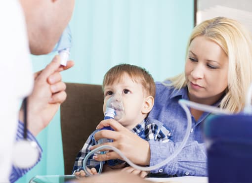 photo of a doctor showing a mother and child how to use a nebulizer
