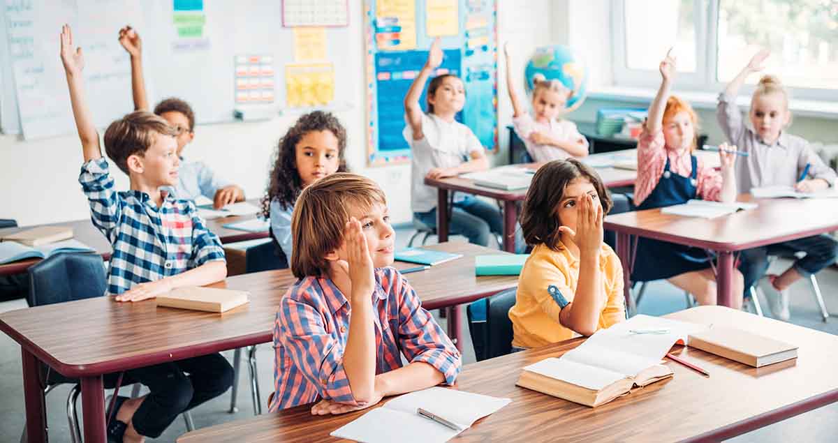 children in school class room raising hands