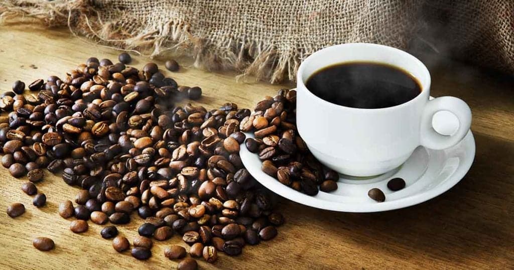 Photo of Hot Coffee cup and roast coffee beans on a wooden table