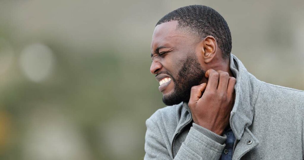 Side closeup view of a Black man with a beard. He