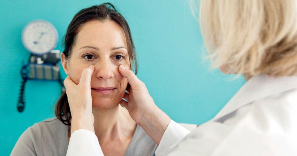 Doctor examining hispanic woman for sinus inflammation.