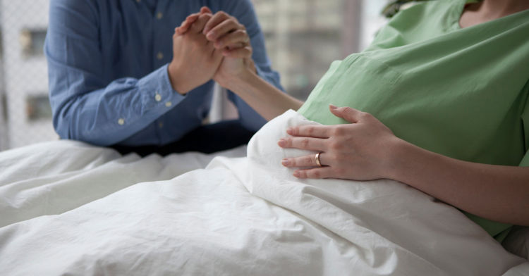 Photo of a young couple holding hands in the delivery room, as they wait for their baby to arrive.